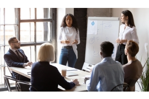 Female leaders sharing information with others sitting at a conference table