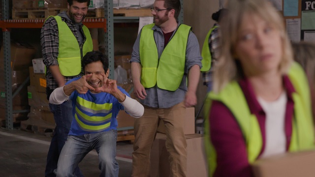 Male warehouse workers leering at female co-worker who looks annoyed by their behavior