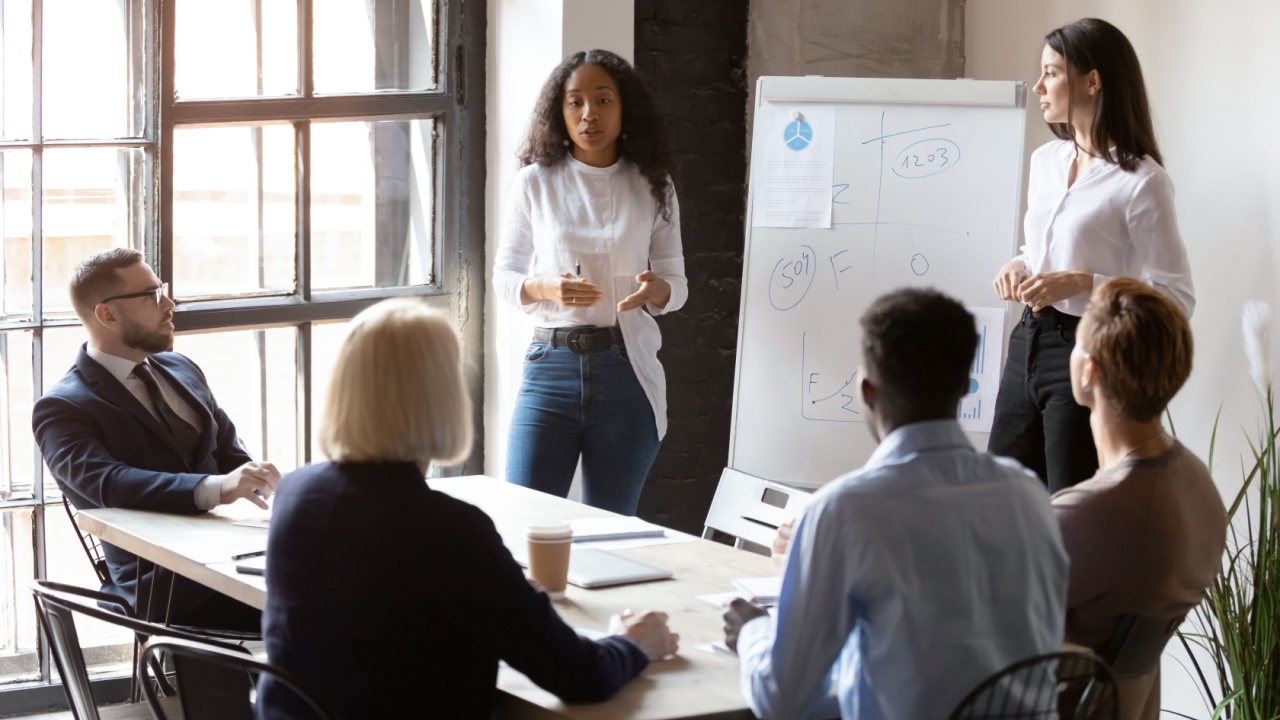 Female leaders sharing information with others sitting at a conference table