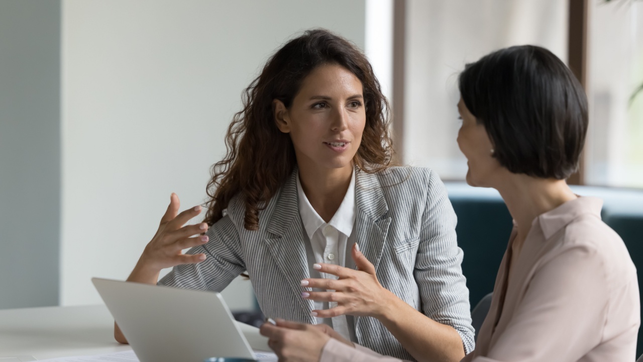 Two female co-workers discussing a work issue