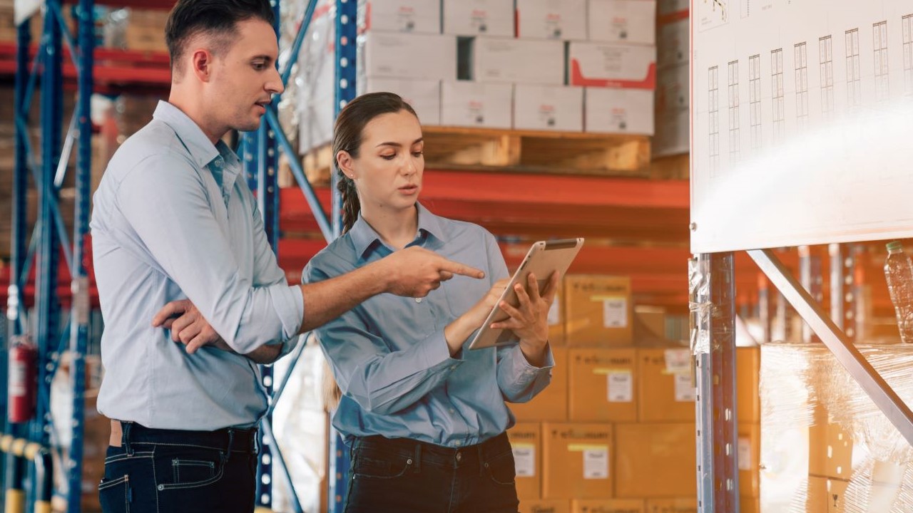 Male and female warehouse managers looking at a checklist on a clipboard